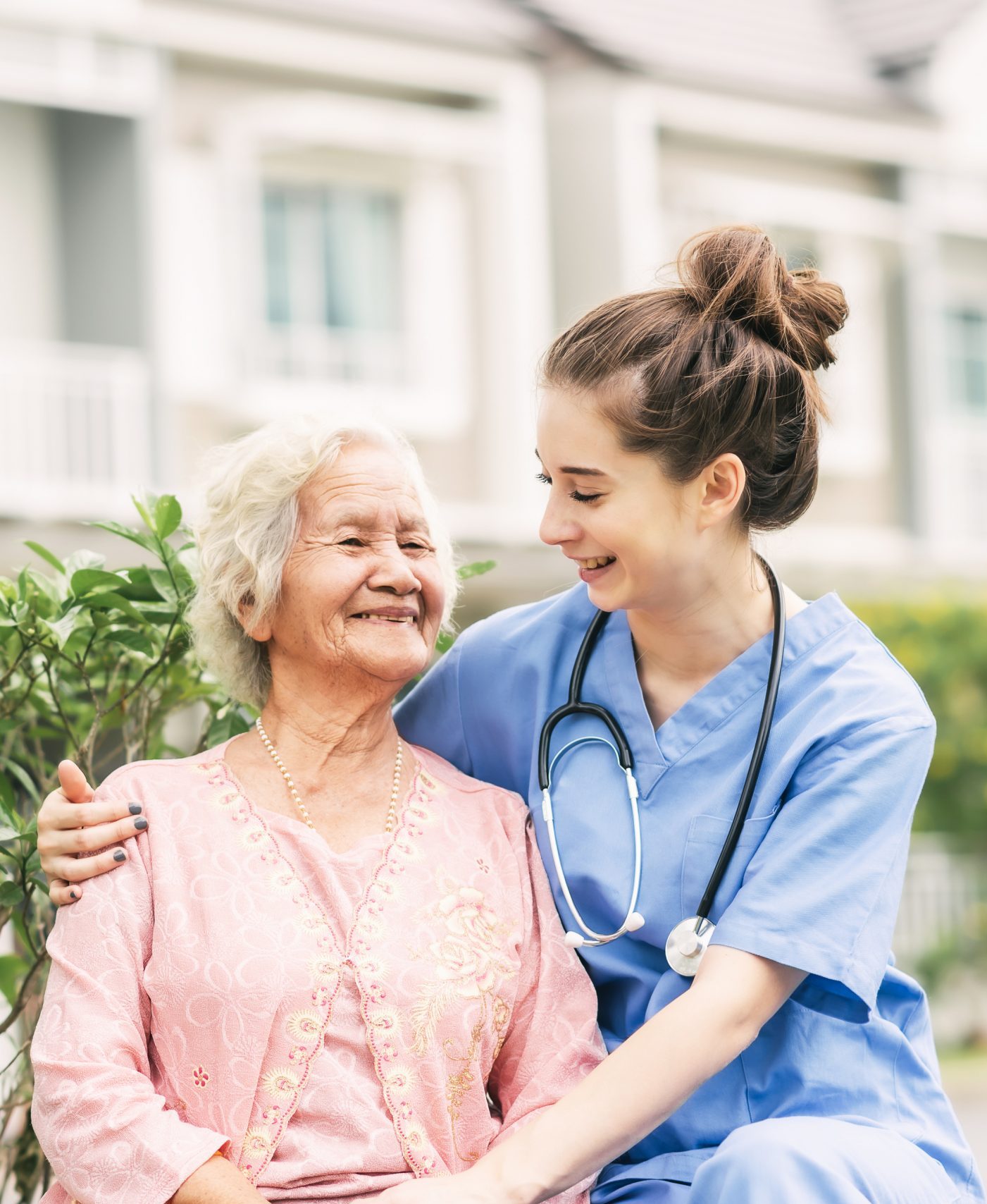 Happy nurse caregiver laughing with Asian elderly woman outdoor